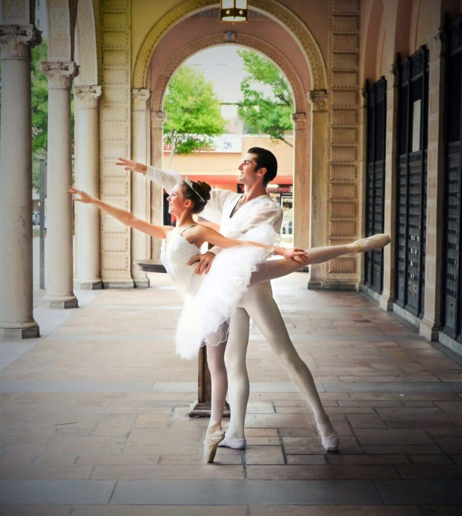 Two people in white outfits are performing a dance.