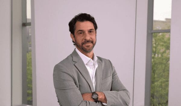 A man in a suit and tie standing with his arms crossed.