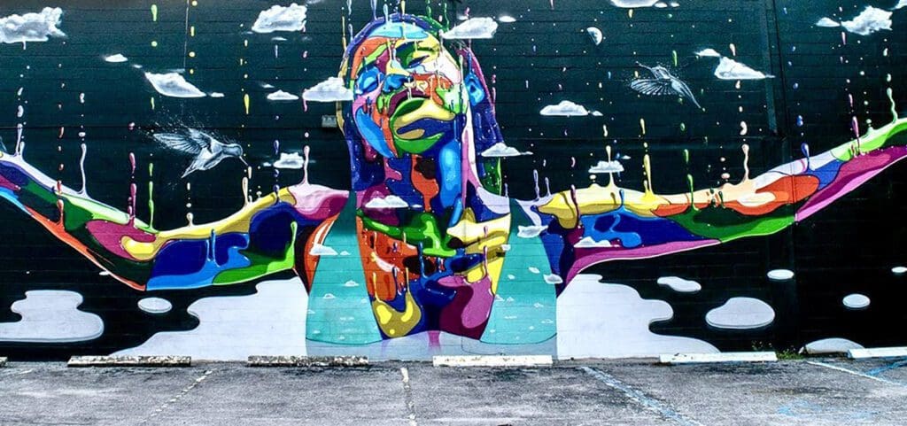 A colorful sculpture of a face in front of a sky background.