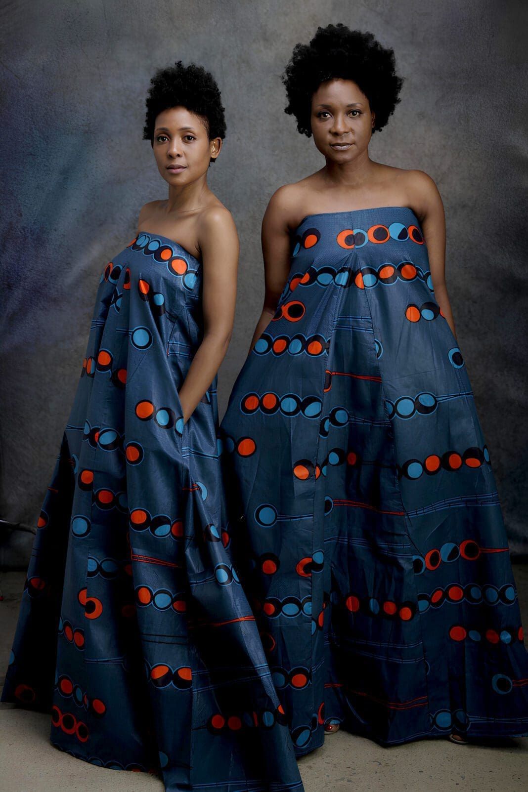 Two women in blue dresses with red circles on them.